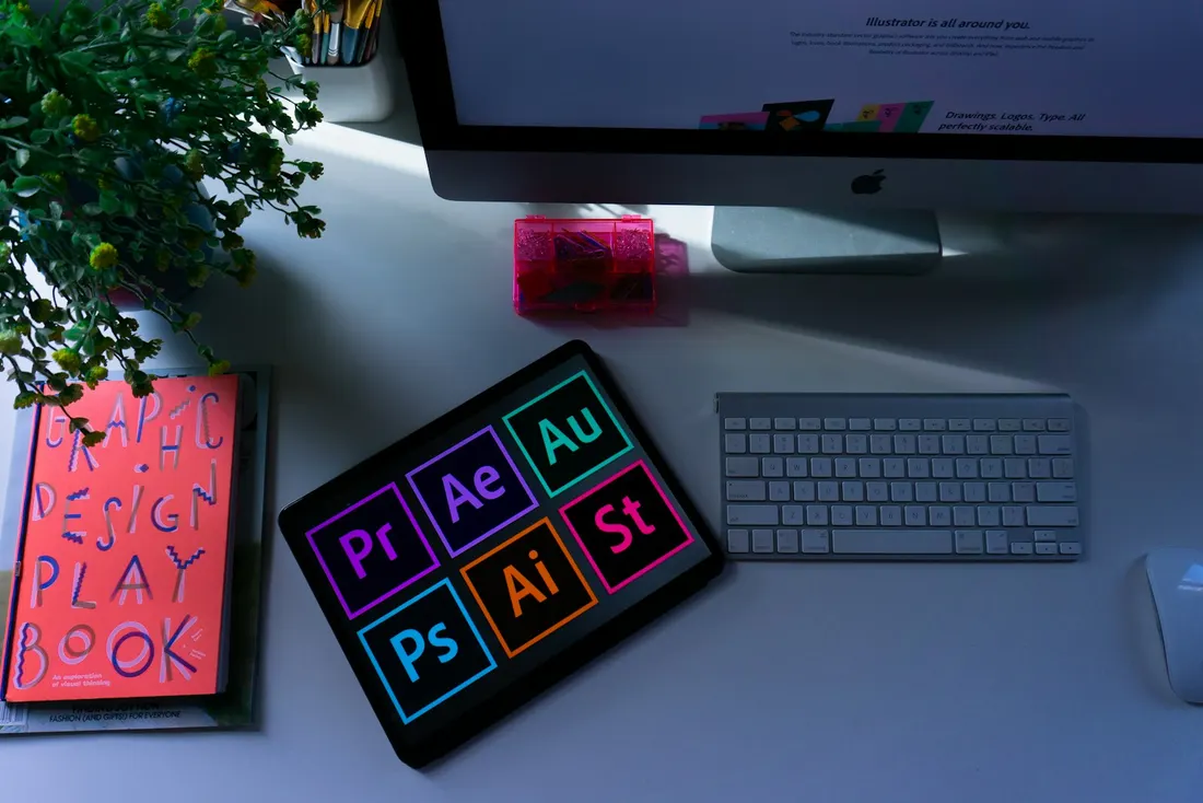 A design playbook book beside a tablet showing creative software icons